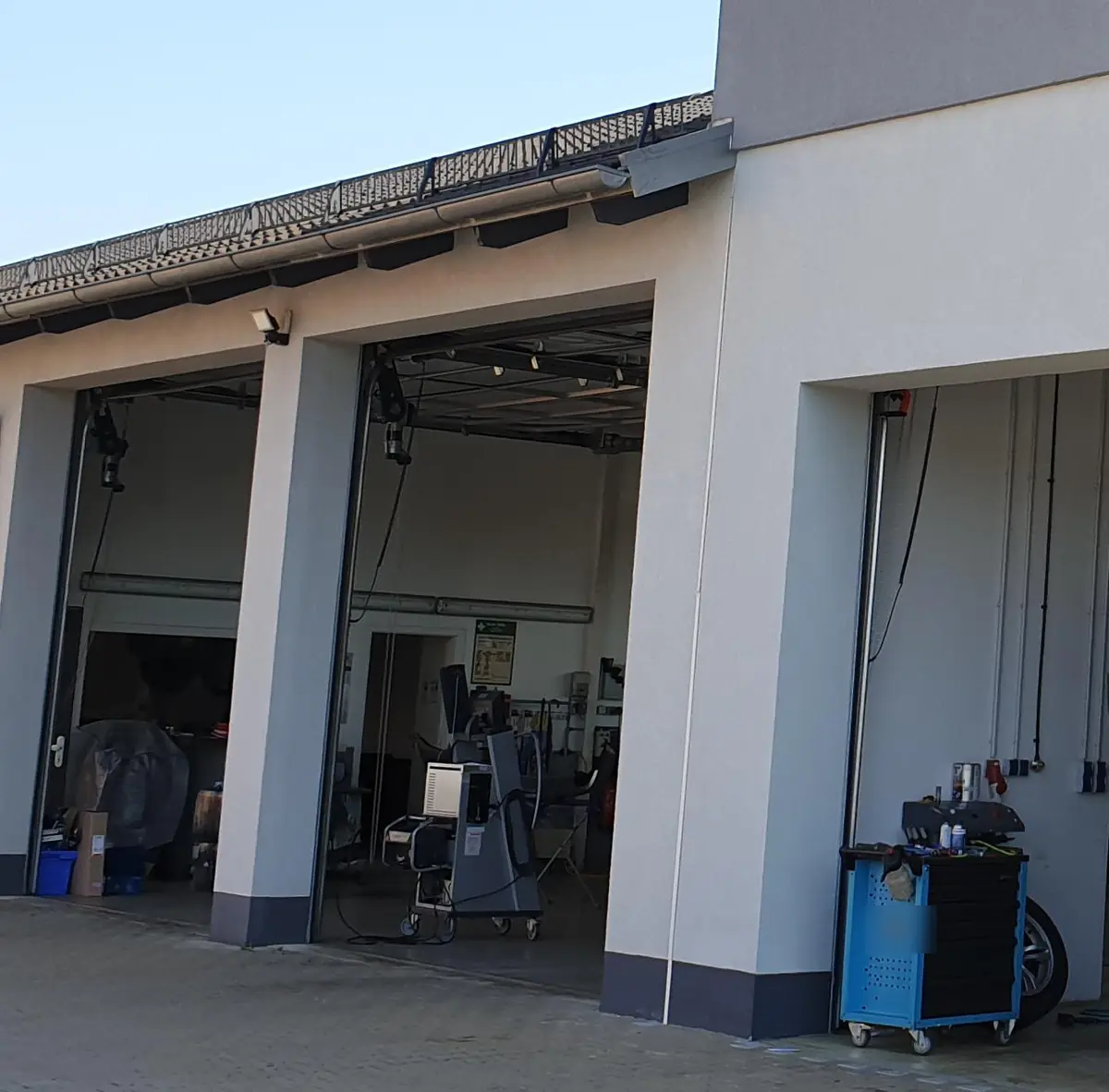 Die Werkstatthallen von Smily’s Autotechnik mit offenen Toren, drinnen Hebebühnen, Prüfgeräte und ein Werkzeugwagen.